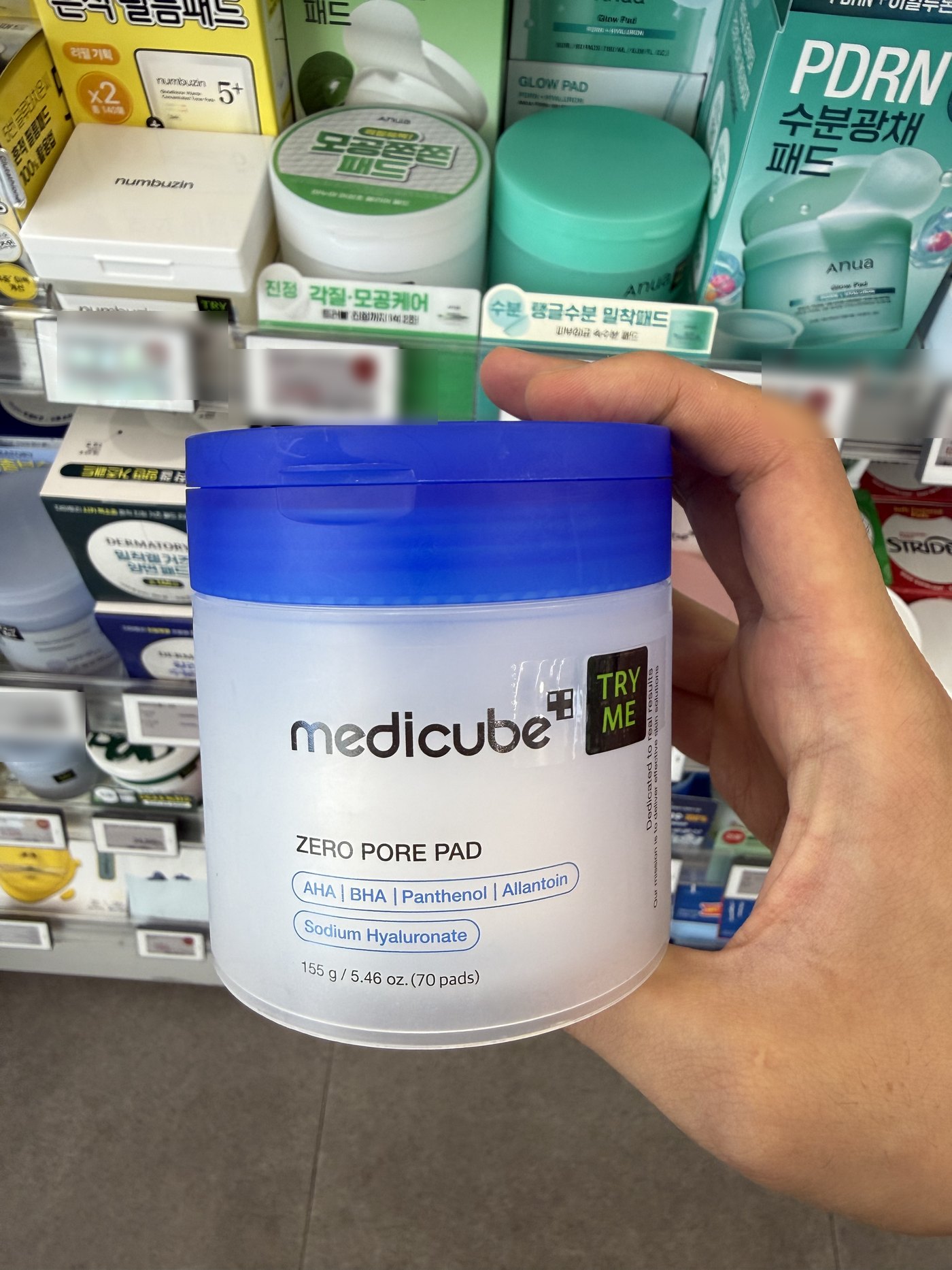 Korean toner pads on an Olive Young shelf in South Korea, including medicube Zero Pore Pad, Anua and numbuzin